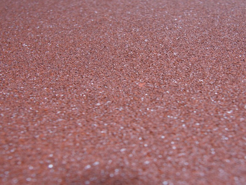 Un magazzino ben organizzato mostra rotoli di pavimentazione per palestre ordinatamente impilati e pronti per la spedizione.